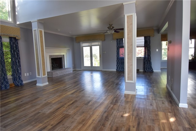 unfurnished living room featuring ornate columns, ornamental molding, dark wood-type flooring, and a fireplace