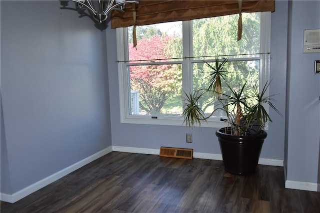 unfurnished room with dark wood-type flooring and a chandelier