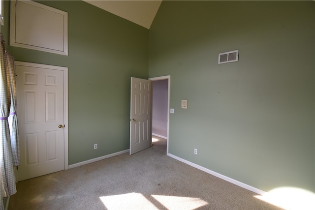 unfurnished bedroom featuring high vaulted ceiling and light colored carpet