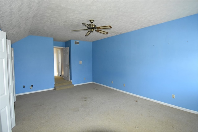 interior space featuring ceiling fan, carpet floors, vaulted ceiling, and a textured ceiling