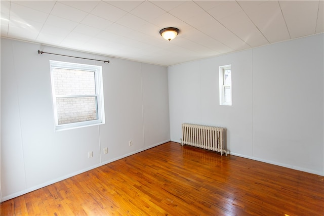 spare room with hardwood / wood-style floors and radiator heating unit