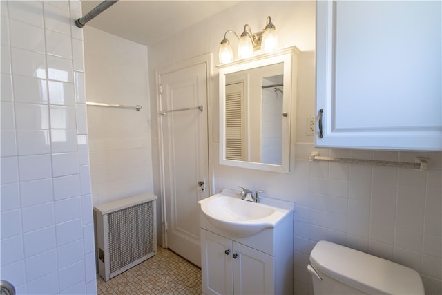 bathroom featuring toilet, radiator heating unit, tile patterned floors, tile walls, and vanity