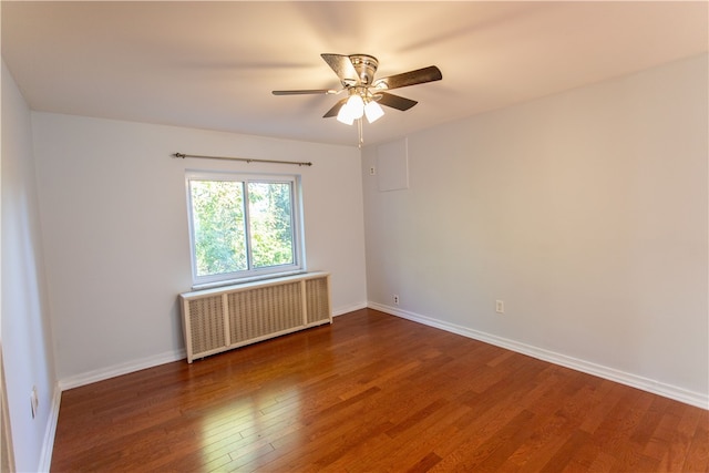 unfurnished room with ceiling fan, dark wood-type flooring, and radiator heating unit