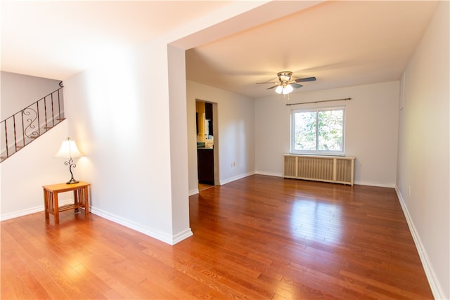 unfurnished room featuring radiator heating unit, hardwood / wood-style floors, and ceiling fan