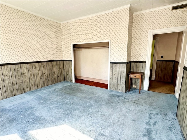 unfurnished bedroom featuring ornamental molding, dark carpet, and wooden walls