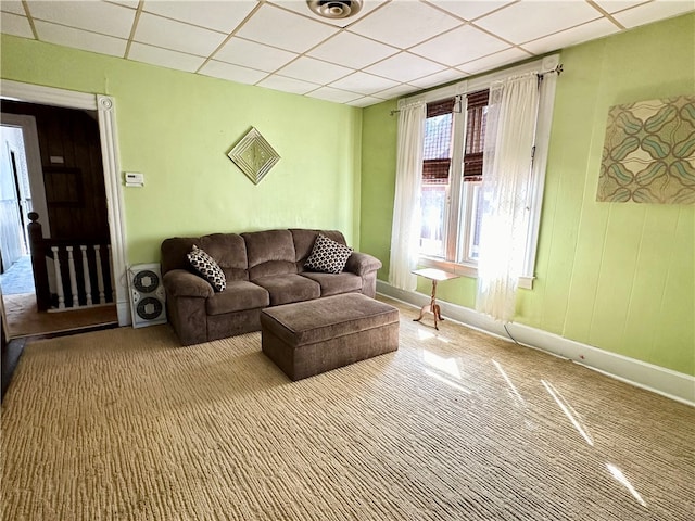 living room featuring a paneled ceiling and carpet flooring