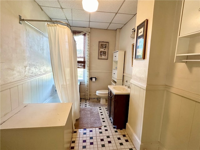 bathroom with toilet, a paneled ceiling, curtained shower, tile patterned floors, and vanity