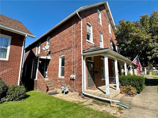 view of side of home featuring a porch and a yard