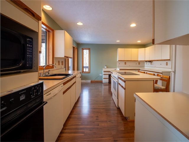 kitchen with a kitchen island, a sink, white cabinetry, light countertops, and black appliances