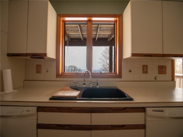 kitchen with dishwasher, light countertops, a sink, and a healthy amount of sunlight