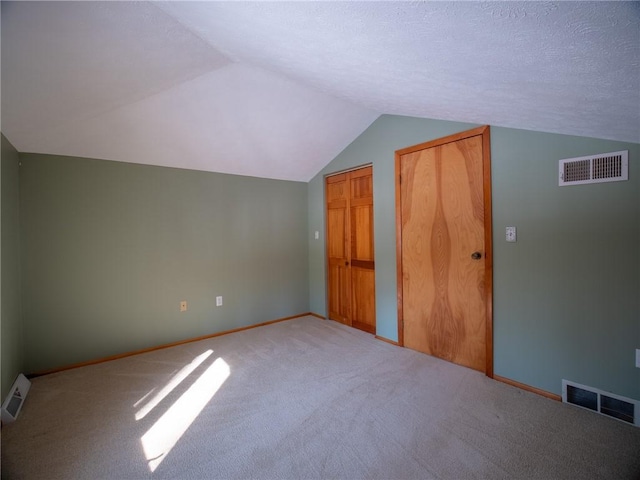 additional living space with lofted ceiling, visible vents, and carpet flooring