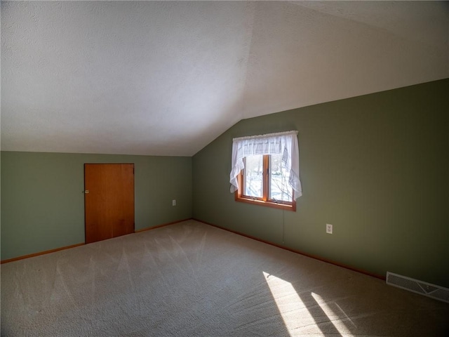 bonus room with baseboards, visible vents, light colored carpet, vaulted ceiling, and a textured ceiling