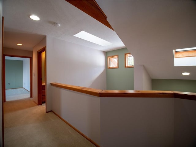 corridor featuring recessed lighting, light carpet, a skylight, an upstairs landing, and baseboards