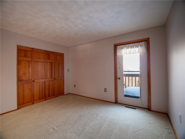 unfurnished bedroom featuring a closet, light colored carpet, visible vents, and baseboards