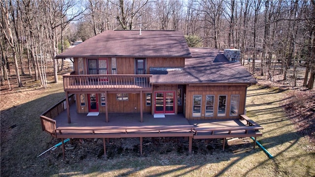 exterior space featuring a shingled roof, a lawn, and a deck