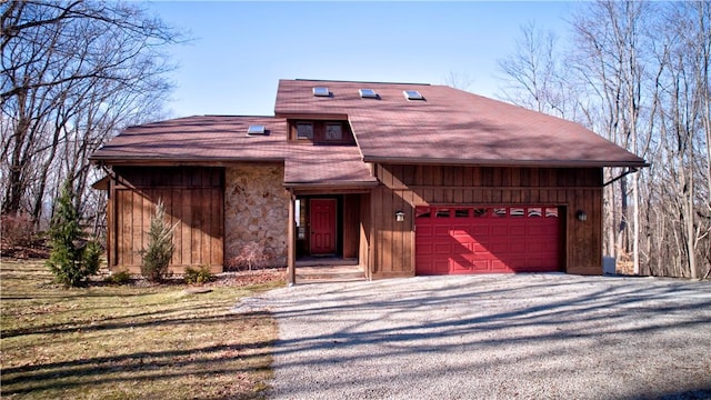 view of front of house featuring driveway, stone siding, and an attached garage