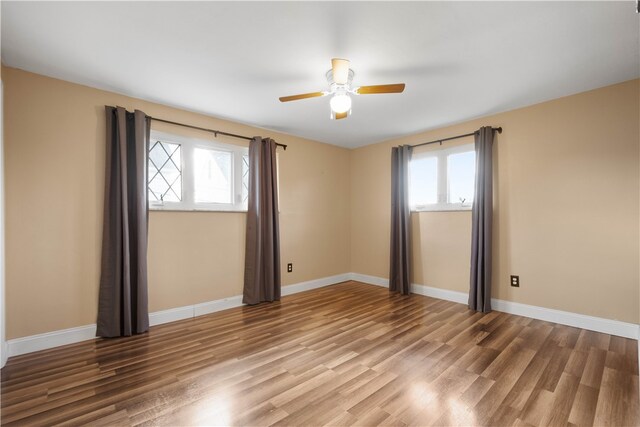 empty room featuring a wealth of natural light, hardwood / wood-style floors, and ceiling fan