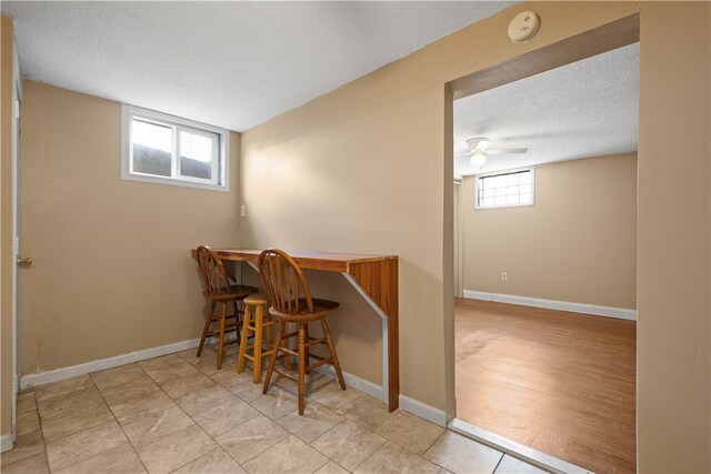 dining space with a textured ceiling, indoor bar, light hardwood / wood-style floors, and a wealth of natural light