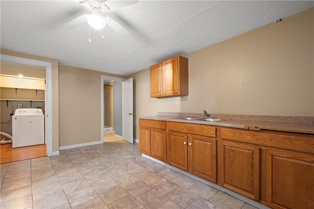 kitchen featuring washer / dryer, a textured ceiling, ceiling fan, and sink