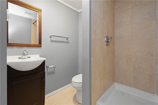 bathroom with tile patterned floors, vanity, a tile shower, and toilet