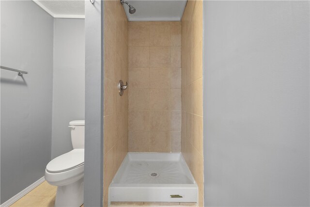 bathroom with tile patterned floors, toilet, and tiled shower