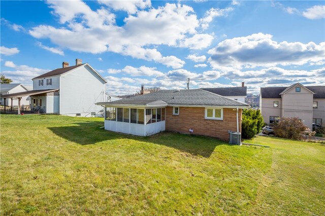 rear view of house with a yard, central AC unit, and a sunroom