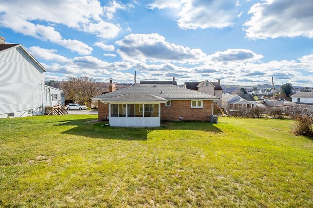 back of house with central AC unit, a lawn, and a sunroom