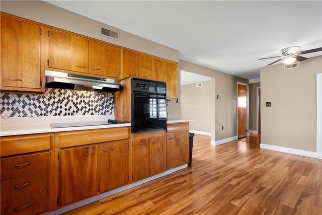 kitchen with electric cooktop, decorative backsplash, oven, and light wood-type flooring