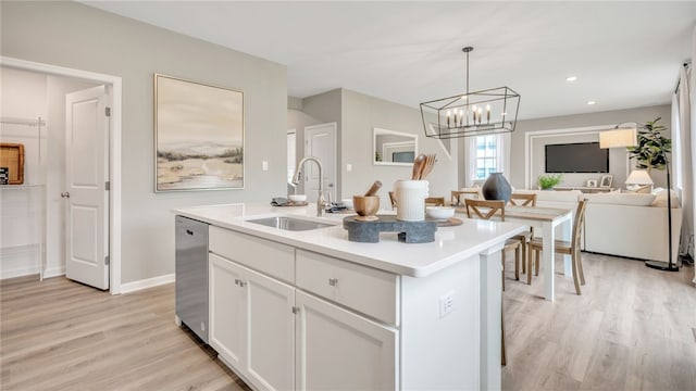 kitchen featuring a kitchen island with sink, stainless steel dishwasher, sink, white cabinetry, and light hardwood / wood-style flooring