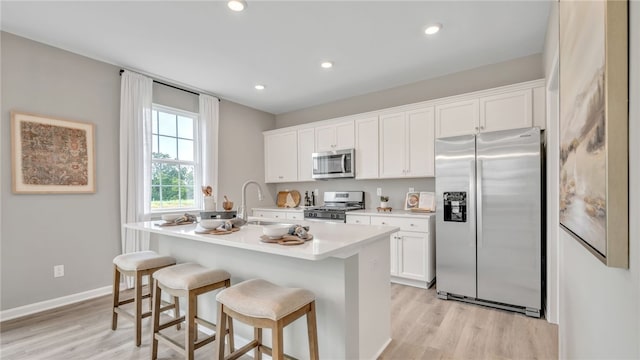 kitchen featuring light hardwood / wood-style flooring, sink, an island with sink, appliances with stainless steel finishes, and white cabinetry