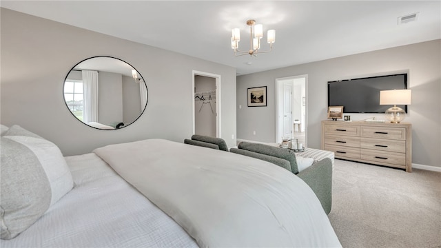 bedroom with a walk in closet, a closet, a chandelier, and light colored carpet