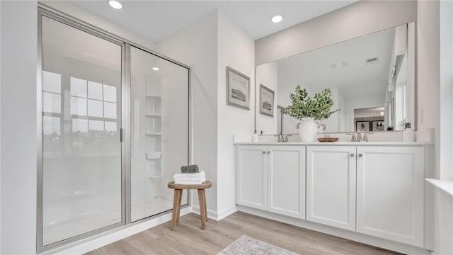 bathroom featuring hardwood / wood-style floors, a shower with shower door, and vanity