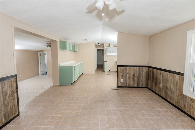 spare room with wood walls, ceiling fan, and vaulted ceiling