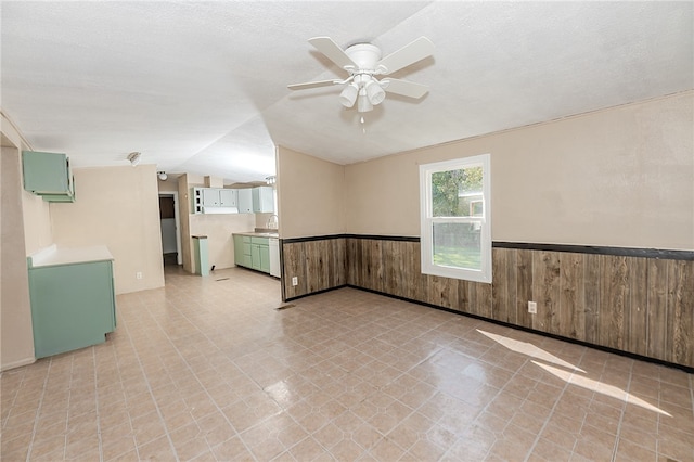 spare room with ceiling fan, a textured ceiling, vaulted ceiling, and wooden walls