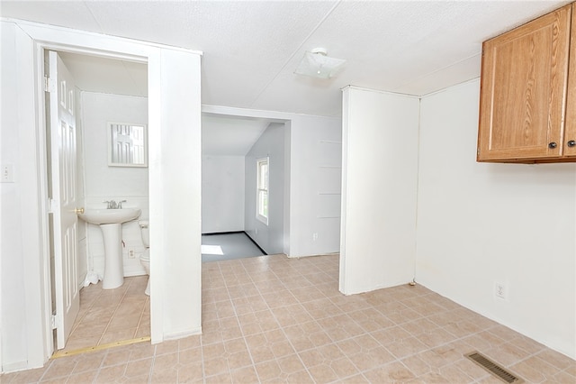 spare room with lofted ceiling and a textured ceiling