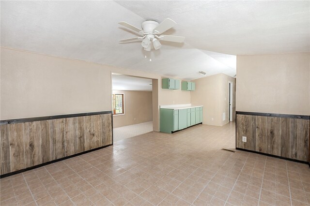 unfurnished room with ceiling fan, lofted ceiling, and wooden walls