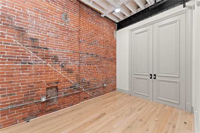 interior space featuring a closet, brick wall, and light hardwood / wood-style flooring