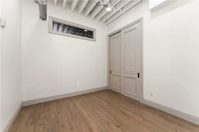 empty room featuring beamed ceiling and hardwood / wood-style floors