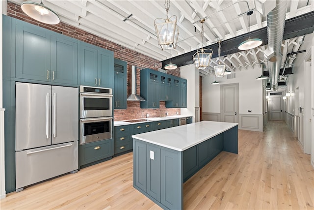 kitchen with appliances with stainless steel finishes, a kitchen island, brick wall, and light wood-type flooring