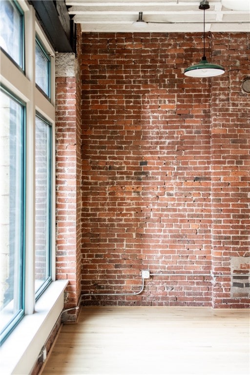 unfurnished room with brick wall and hardwood / wood-style floors