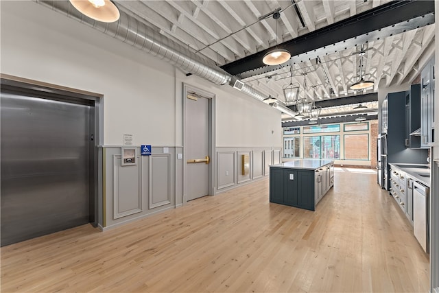 kitchen featuring light hardwood / wood-style flooring, elevator, hanging light fixtures, and a kitchen island