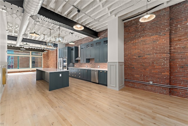 kitchen featuring pendant lighting, appliances with stainless steel finishes, light wood-type flooring, and a kitchen island