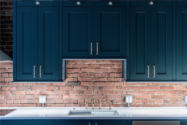 kitchen featuring sink, brick wall, and blue cabinetry