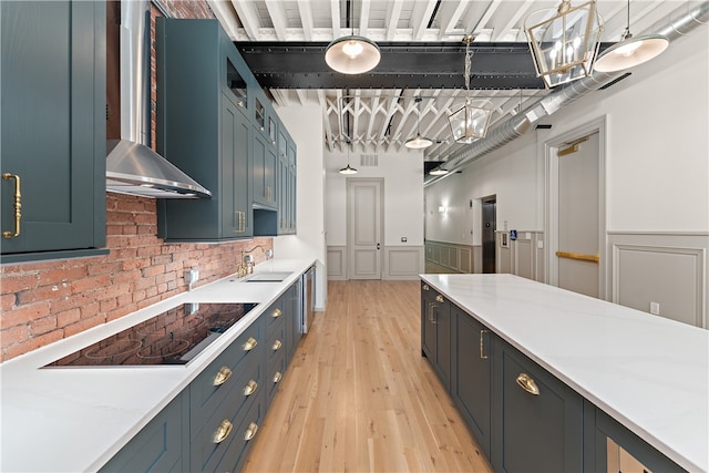 kitchen with black electric cooktop, light stone countertops, decorative light fixtures, and light hardwood / wood-style flooring