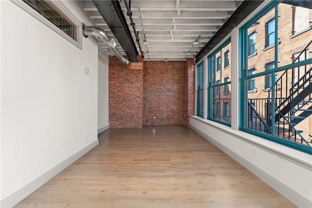 hallway featuring wood-type flooring and brick wall