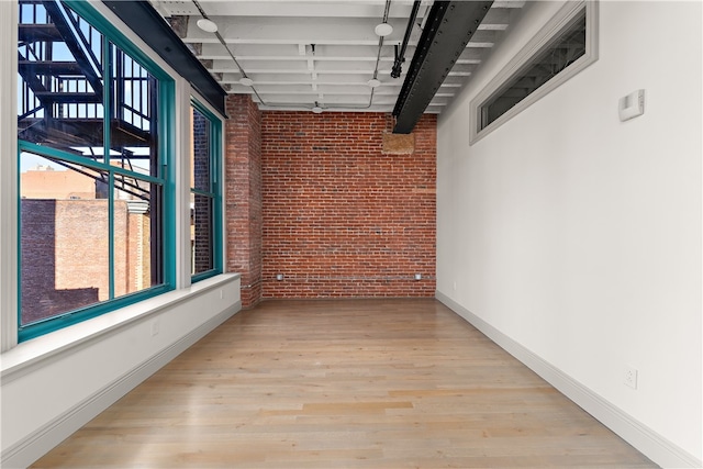 hall with brick wall and light wood-type flooring