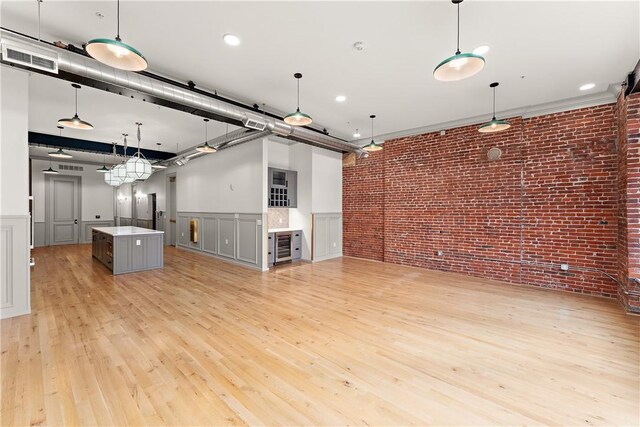 915 Liberty Ave Unit 5, Downtown Pgh, PA 15222 - unfurnished living room featuring brick wall, light wood finished floors, a wainscoted wall, and a decorative wall