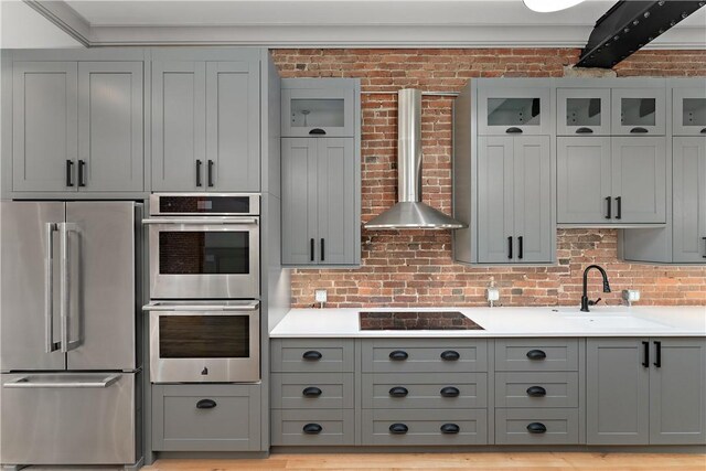 915 Liberty Ave Unit 5, Downtown Pgh, PA 15222 - kitchen with appliances with stainless steel finishes, wall chimney range hood, a sink, gray cabinets, and brick wall