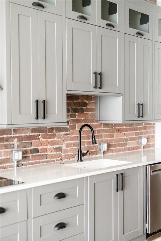 915 Liberty Ave Unit 5, Downtown Pgh, PA 15222 - kitchen featuring a sink, light countertops, decorative backsplash, and glass insert cabinets