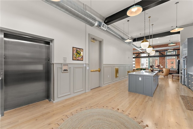 kitchen featuring light wood-type flooring, elevator, decorative light fixtures, and a center island